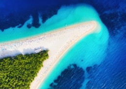 Aerial view of a sandy beach and turquoise waters at a picturesque coastline, ideal for sailing and sunbathing.