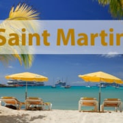 Saint Martin tropical beach scene with palm trees, yellow umbrellas, and boats on turquoise water. Perfect vacation spot.