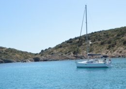 Sailboat anchored in serene blue water near rocky coast, ideal for sailing adventures and peaceful escapes.