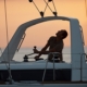 Sailor adjusting sail on a yacht at sunset, mastering navigation for a smooth maritime journey.