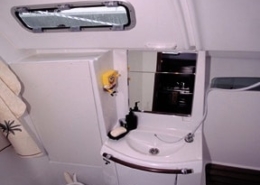 Sailboat bathroom interior with compact sink, mirror, and toilet, showcasing efficient design for marine use.