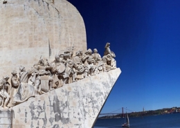 Monument of Discoveries sculpture in Lisbon with sailors set against a clear blue sky and a view of the Tagus River.