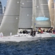 Sailboats racing in the ocean with crews managing sails, showcasing competitive sailing dynamics and teamwork.