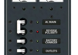 Marine electrical panel with switches for AC main, reverse polarity, battery charger, outlets, and spare.