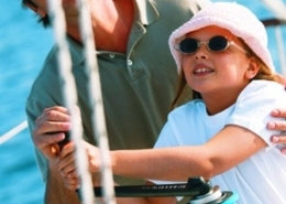 Father and daughter enjoying sailing, adjusting ropes on a sunny day at sea.