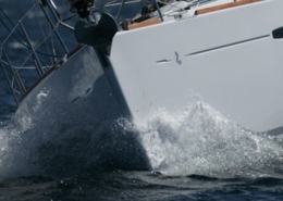 Sailboat cutting through ocean waves, showcasing the bow's sleek design and dynamic sailing movement.