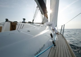 Sailing on a modern yacht at sunset, with a person relaxing on deck and the sea stretching to the horizon.