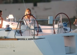 Three people having a relaxed conversation on a sailboat at sunset.