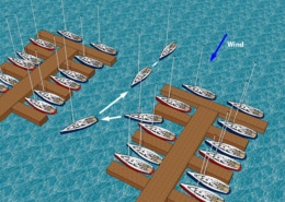 Sailboats navigating between docks on a sunny day, with wind direction marked, illustrating docking maneuvers.