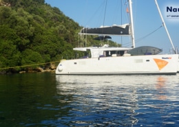 Catamaran anchored near lush island for sailing education with NauticEd branding.