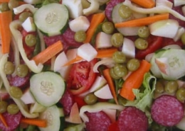 Colorful fresh vegetable and salami salad with cucumbers, carrots, tomatoes, and peas for a healthy, vibrant meal.