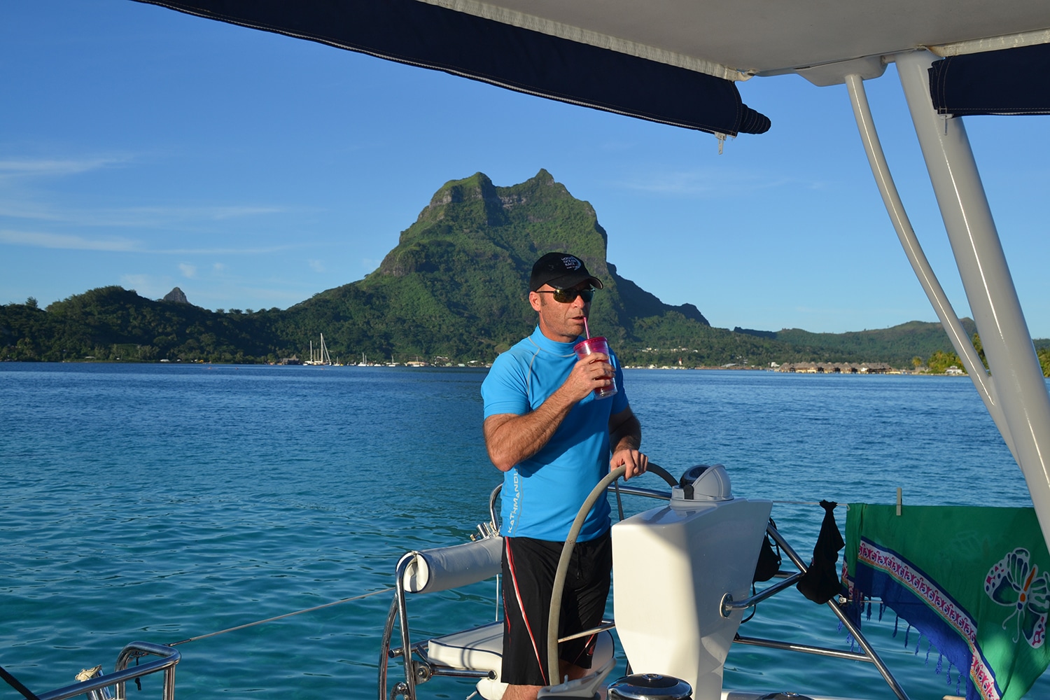 Grant enjoying a drink on a yacht with scenic mountain view in Bora Bora backdrop.