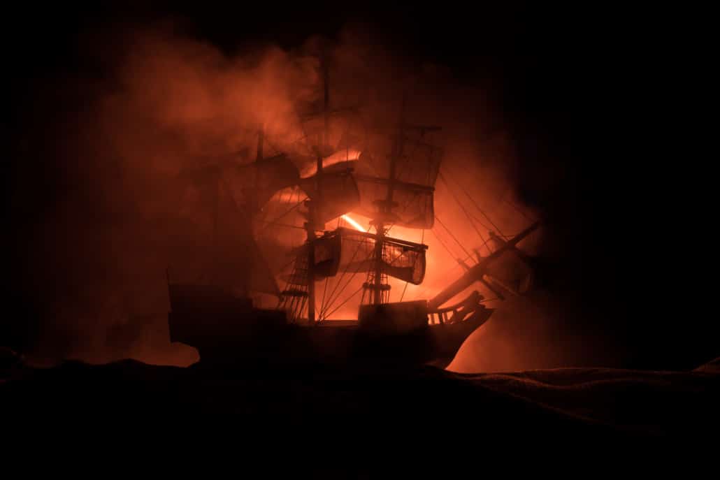 Silhouette of a ship in flames at sea, engulfed in dramatic red-orange smoke, symbolizing peril and adventure.