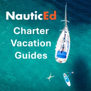 Sailboat charter vacation with NauticEd guides. Aerial view of sailboat, swimmers, and paddleboard in clear blue water.