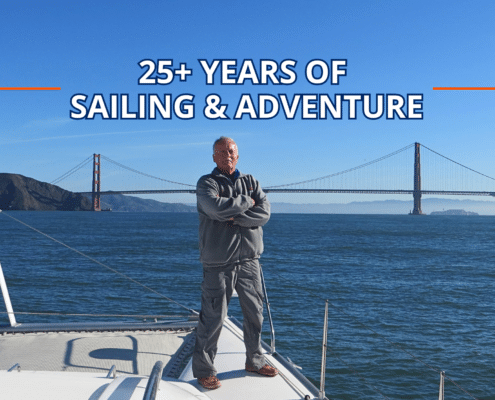 Man standing on sailboat with Golden Gate Bridge in the background, celebrating 25+ years of sailing adventure.