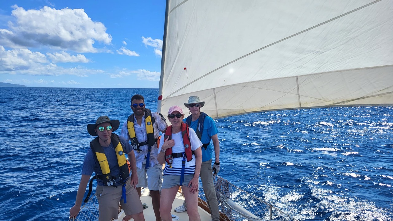 Group sailing adventure on a sunny day, enjoying the open sea under clear blue skies.