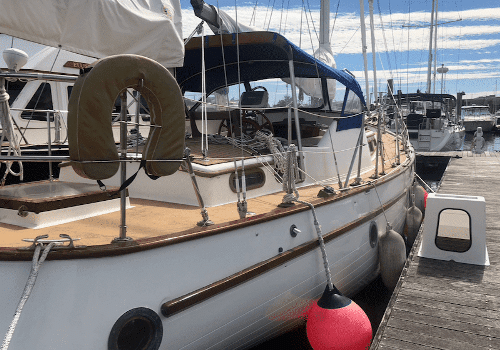 Sailboat docked in marina with clear skies, featuring classic wooden deck and colorful buoys. Perfect for sailing enthusiasts.