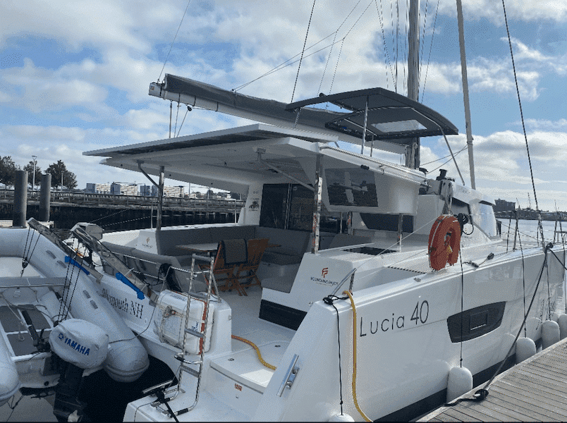 Modern catamaran yacht, Lucia 40, docked at marina under clear skies. Ideal for luxury sailing adventures.