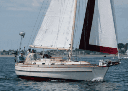 Sailboat cruising on calm waters near shore under blue sky, capturing the essence of maritime adventure and relaxation. regatta racing tips