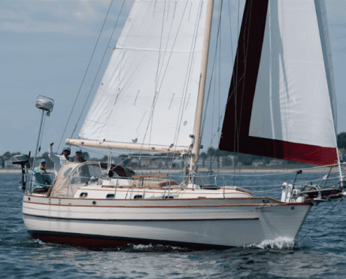 Sailboat cruising on calm waters near shore under blue sky, capturing the essence of maritime adventure and relaxation. regatta racing tips