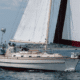 Sailboat cruising on calm waters near shore under blue sky, capturing the essence of maritime adventure and relaxation. regatta racing tips