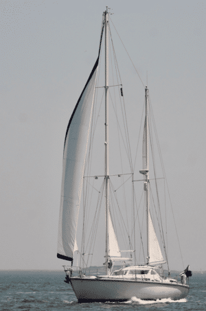 White sailboat gliding on open sea under clear skies, showcasing elegant sails and sleek design.