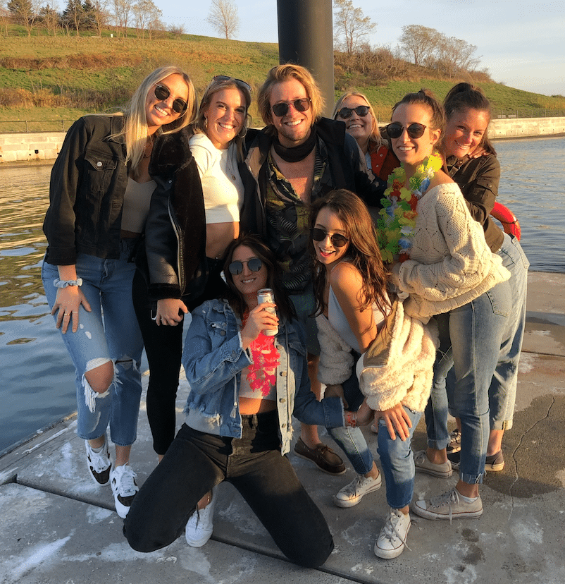 A cheerful group of friends enjoying a sunny day by the water, wearing casual outfits and colorful accessories.