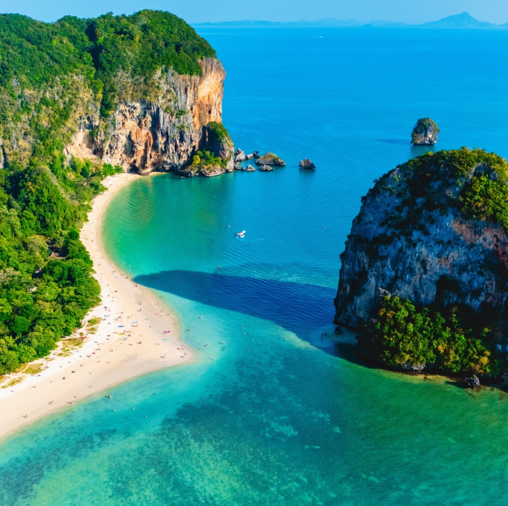 Tropical bay with turquoise water, sandy beach, and lush cliffs, perfect for sailing and exploring serene paradises.