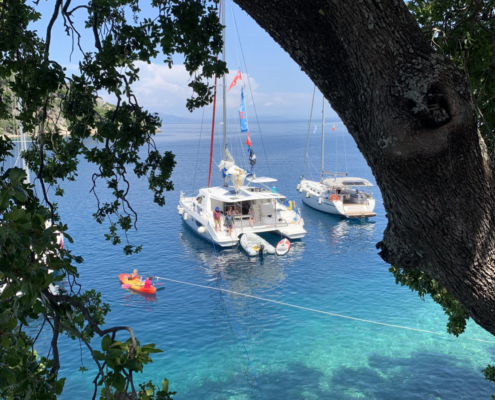 Sailboats anchored in clear blue water, surrounded by lush greenery in a tropical paradise.