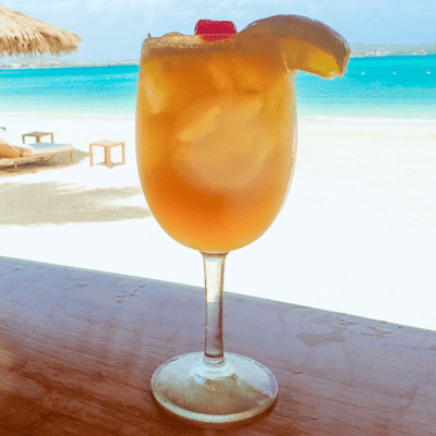 Tropical cocktail on a beachside table overlooking turquoise waves, perfect for a sailing getaway.