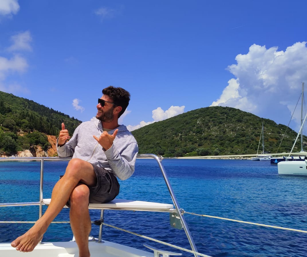 Man relaxing on a sailboat with scenic ocean view, enjoying the sunny day in a tropical paradise.