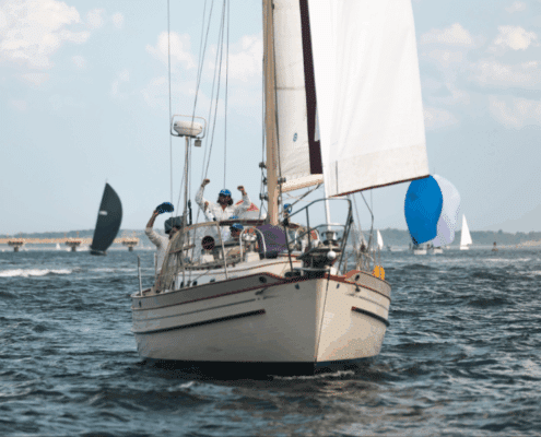 Crew celebrating on a sailboat race, clear skies and other sailboats in the background.