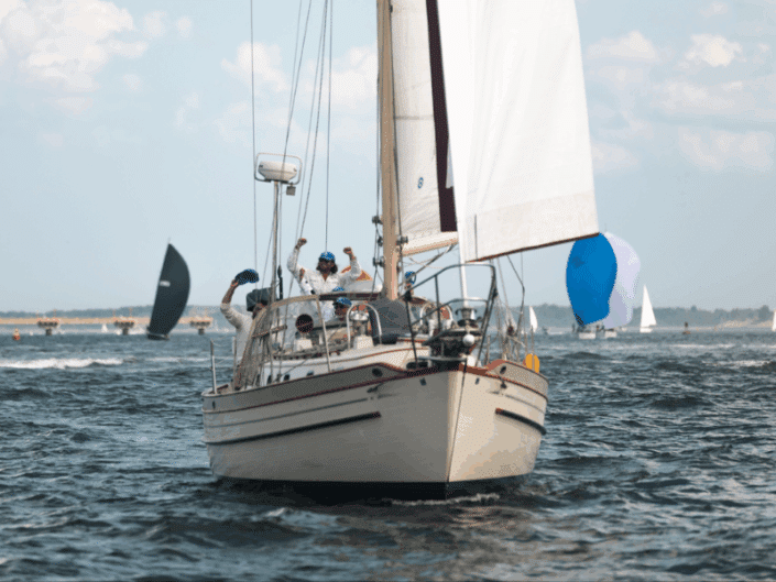 Crew celebrating on a sailboat race, clear skies and other sailboats in the background.