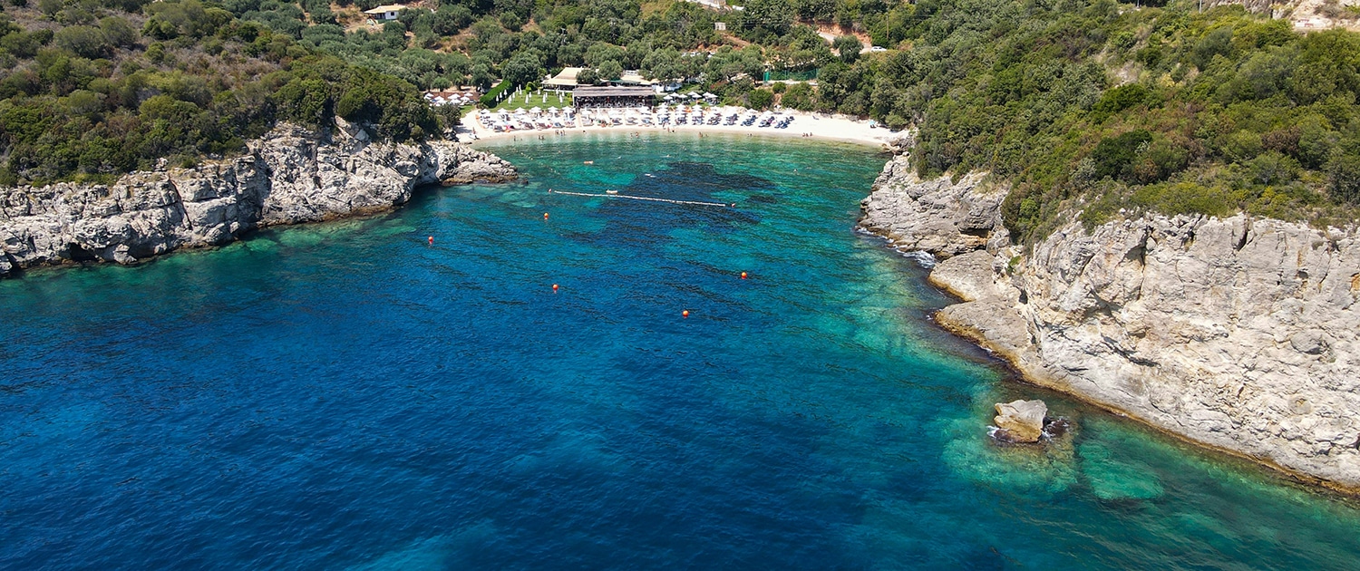Aerial view of a secluded beach cove with turquoise waters and lush greenery, perfect for sailing adventures.