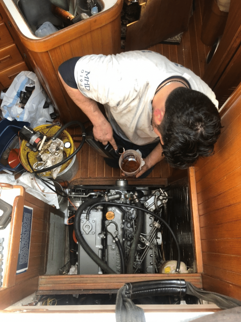 Man performing maintenance on sailboat engine in cabin, ensuring smooth sailing with precision and care.