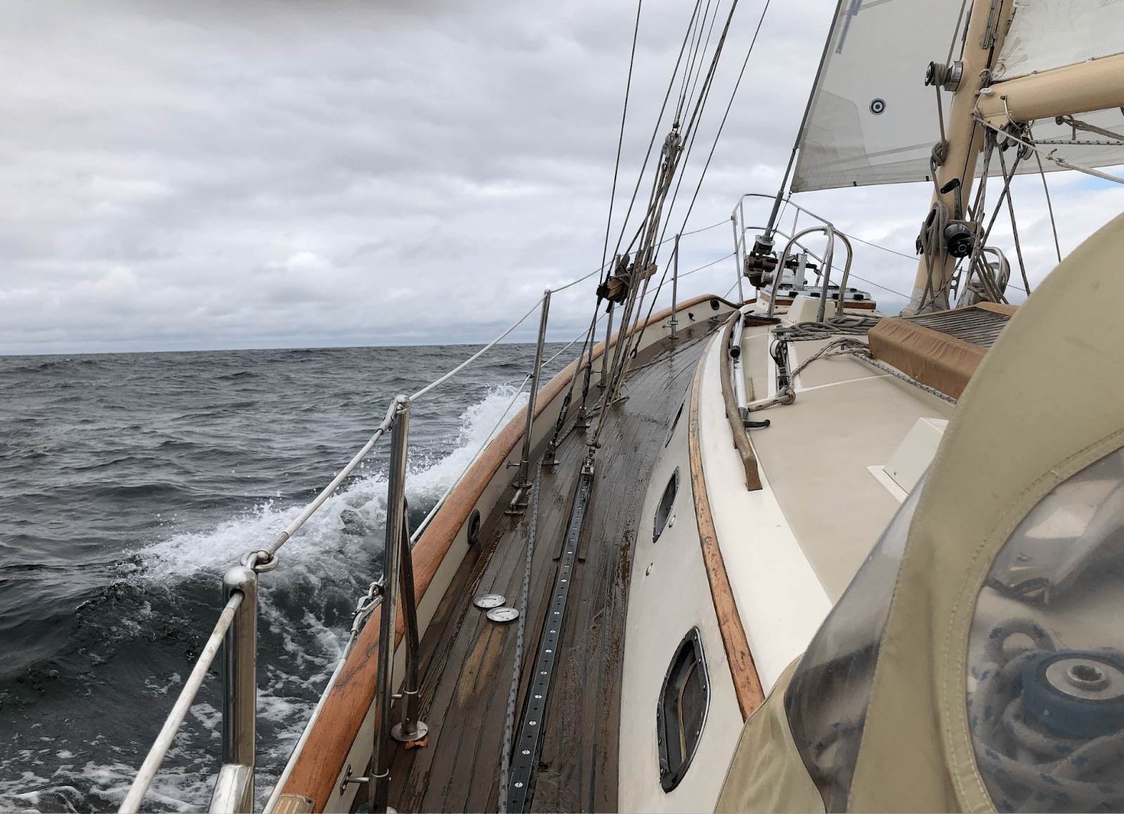 Sailing boat on the open sea with wooden deck and sails in a cloudy sky, capturing the essence of nautical adventure.