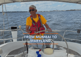 Person sailing with a smile under sunny skies, wearing a red vest and yellow shirt, captioned From Mumbai to Maryland.