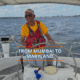 Person sailing with a smile under sunny skies, wearing a red vest and yellow shirt, captioned From Mumbai to Maryland.