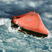 blog-featured-image-3-Life Rafts 101 Orange lifeboat rides rough ocean waves under stormy skies.