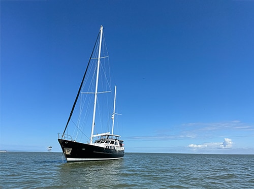 Sailboat on calm sea under clear blue sky, showcasing serene sailing adventure and maritime tranquility.