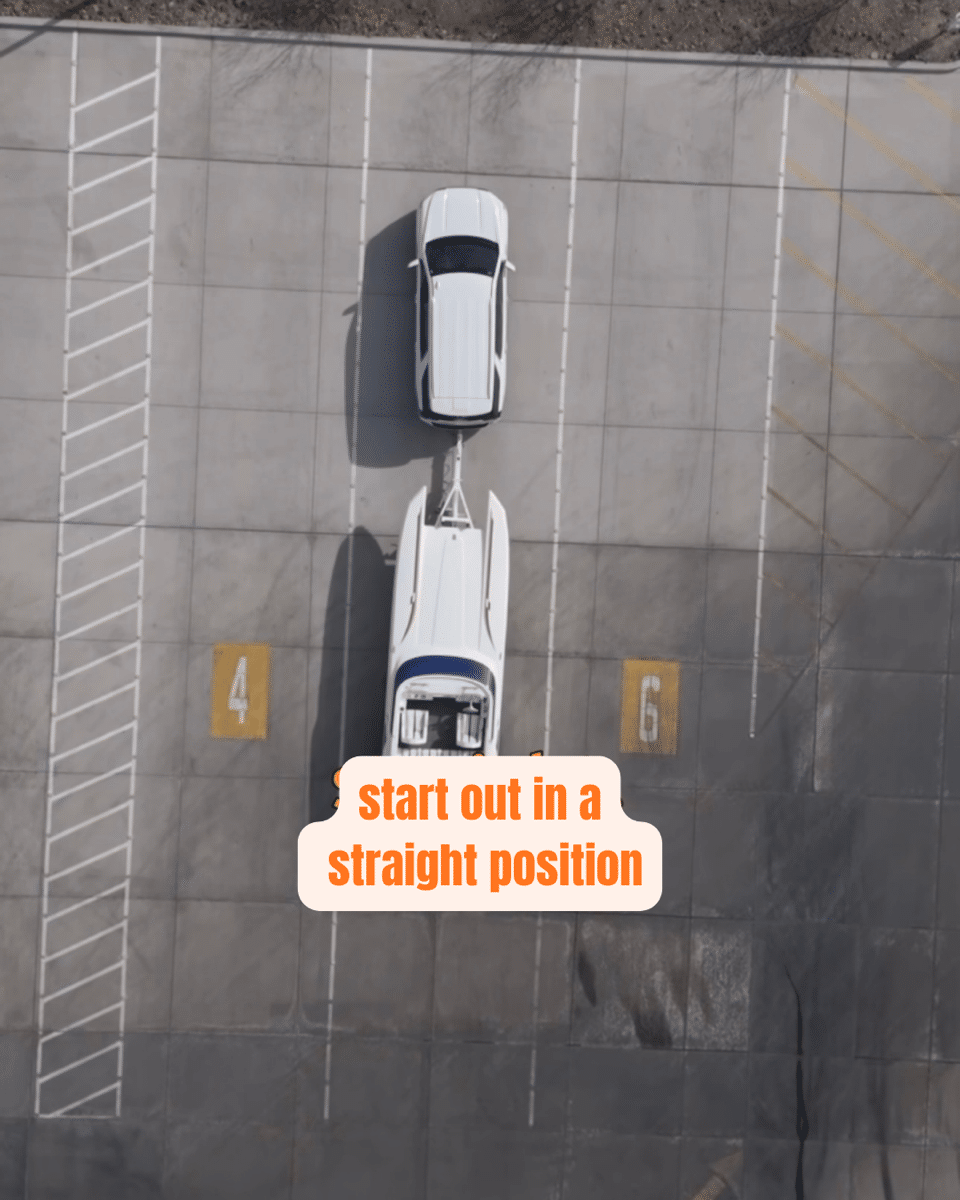 2 Top view of a car towing a boat on a trailer in a parking lot with overlay text: start out in a straight position.