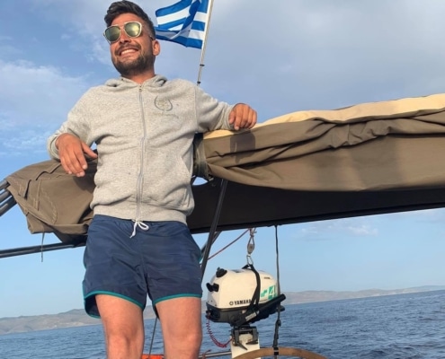 George Sakkas Man enjoying sailing near Greek coast under a sunny sky.