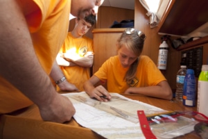 Sea Scouts Navigating Sea Scout sailors planning a route with a nautical chart onboard, teamwork in navigation training.