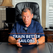 Why Choose NauticEd for Sailing Education? Man in a navy polo giving a presentation titled Train Better Sailors at a desk.