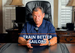 Man in a navy polo giving a presentation titled Train Better Sailors at a desk.