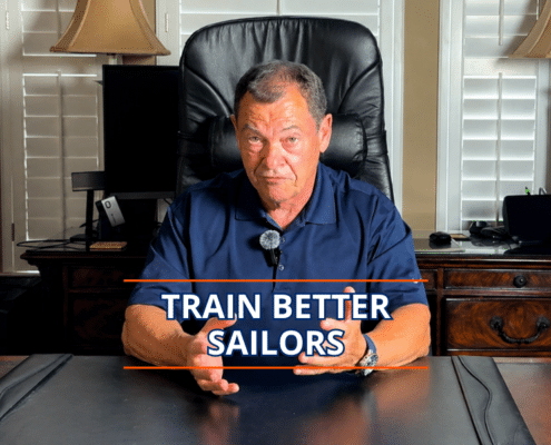 Man in a navy polo giving a presentation titled Train Better Sailors at a desk.