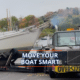 Truck transporting sailboat on road, sign reads Oversize Load, with Move Your Boat Smart text overlay.