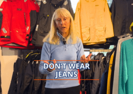 Woman giving sailing attire advice, standing in front of waterproof jackets, with text overlay: Don't Wear Jeans.