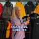Person comparing sailing jackets: Coated vs. Gore-Tex, with various colors in the background.