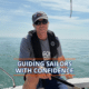 Experienced sailor steering a boat under blue skies, promoting sailing confidence and skills.
